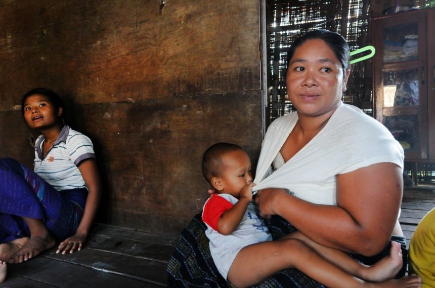 Ei Shel, 30, holds her child in her Hlaing Tharyar home. 