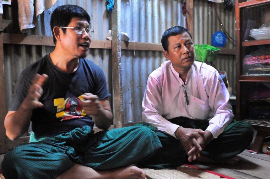 Local National League for Democracy representatives Nyunt Win (wearing Aung San shirt) and Hla Htay sit in the Hlaing Tharyar squatter settlement.